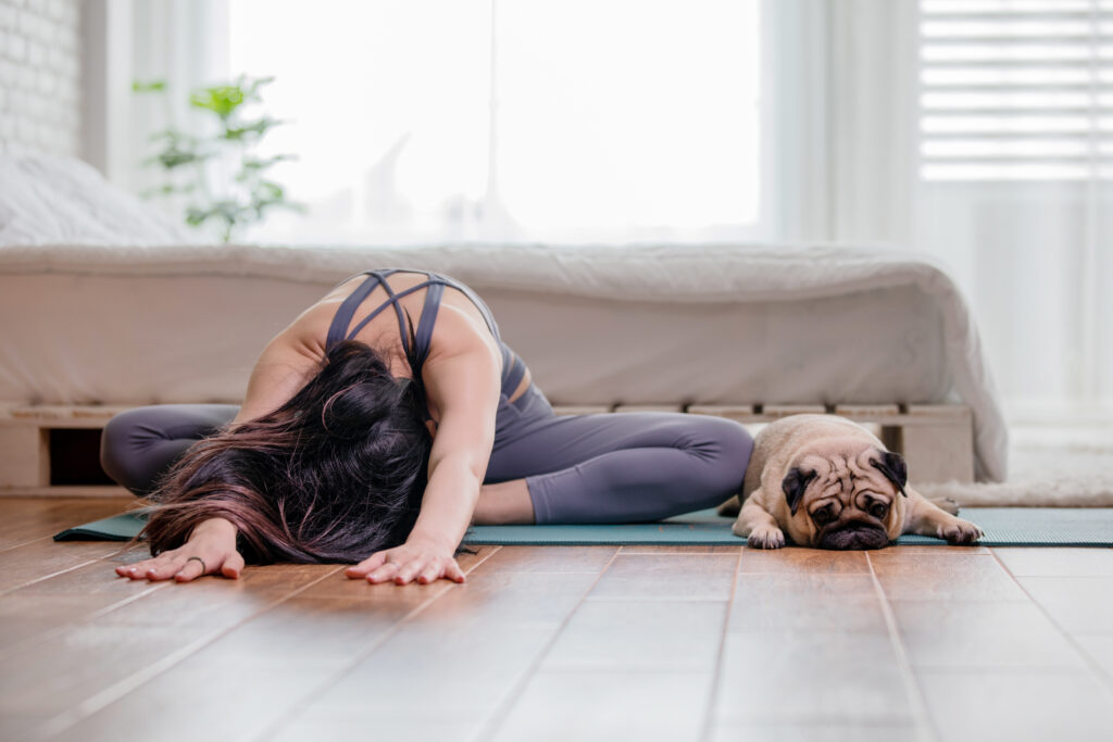 une femme fait du dog yoga avec son carlin